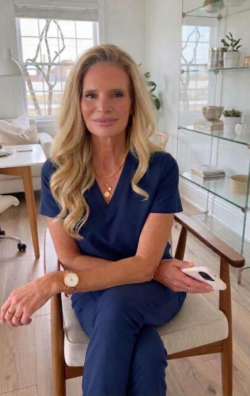 Valorie, the nurse founder of Wellness in Chaos, wearing navy scrubs in a bright, modern wellness room